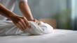 © Alexander - Close-up of womanâs hands neatly tucking white bed sheet on clean bed in bright minimalist bedroom, morning natural light illuminating soft cotton texture, concept of cleanliness,