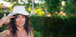 © jovannig - Beautiful woman in cowboy hat and white dress posing in green garden with sunlight