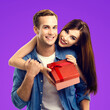 © vgstudio - Holiday sales, price discounts, celebrating ad concept - happy smiling cute couple showing pointing red gift box. Portrait of young man, woman, isolated against purple background. Square image