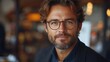 © Sameul - Confident man with glasses and beard in warm indoor setting, stylish casual look with natural light and soft background bokeh created with AI