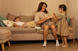 © Vagengeim - Mother and daughter interact while son plays on sofa