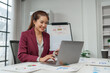 © crizzystudio - Businesswoman smiling while working on laptop in office
