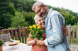 © Halfpoint - Portrait of mature son bringing bringing flowers to old mother.