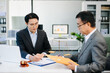 © Nuttapong punna - Lawyer consulting client in modern office, reviewing documents with gavel and scales on desk. Ideal for law, finance, consulting, or corporate themes.