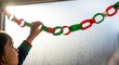 © Konate - Child near window holding redgreen paper chain Sunlight streams through the glass