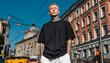 © Jack - Young man with tattoos wears an oversized black t-shirt and white pants. Streetwear fashion photo captured on urban city street. Model poses confidently, showing off apparel style.