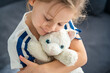© dtatiana - Portrait of a child holding a well-worn soft toy in their hands. Emotional attachment to a beloved object that brings comfort, trust, and a feeling of safety in early childhood.