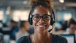 © maxximmm - A woman with a headset sits in a busy office with a headset on her head. The office is filled with desks and other office workers, creating a bustling environment.