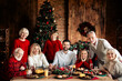 © deagreez - Family gathers for a cozy Christmas dinner by the tree in a warm loft living room with garlands lights and joyful smiles during the festive eve