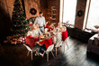 © deagreez - Family gathers for a warm Christmas dinner beside a decorated tree in a cozy loft style home with gifts lights and festive decorations