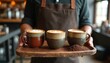 © Vadym - Barista serves three artisan coffee cups with latte art on a rustic wooden tray. Cozy cafe ambiance, selection of hot drinks, fresh brew. Enjoyable morning or afternoon.