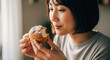 © ProArt Studios - Happy Japanese woman savoring a sweet cream puff, her expression showing pure delight while enjoying a delicious dessert.