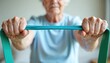 © Vadym - Elderly person grips turquoise resistance band, pulling it taut. Active senior woman works out, strengthening arms and upper body. Focus on mobility and health.