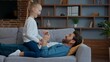 © Yuliia - Caucasian family at home loving father with little playful girl tickling dad with active child kid daughter playing tickle on couch sofa funny entertainment in living room enjoying spending good time