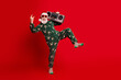 © deagreez - Festive Santa in Christmas pajama with boombox dances playfully against red background for holiday cheer and seasonal shopping vibes