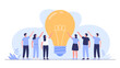 © Qadeer - Diverse group of people collaborating and holding up a giant illuminated light bulb symbolizing a shared innovative idea