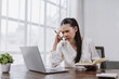 © amnaj - Asian woman experiencing confusion and stress while studying or working on a laptop, needing to solve a problem
