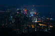 © AmazingAerialAgency - Aerial view of a vibrant metropolis where a symphony of illuminated skyscrapers pierce the dark sky, reflecting on the tranquil harbor waters, Hong Kong, Hong Kong.