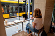 © sepy - Rear view shot of a woman sitting in a cafe and using her laptop