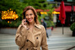 © sepy - Brunette haired woman walking in city street on an autumn day and using her smartphone