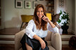 © sepy - Confident and attractive middle aged woman relaxing in an armchair in her modern home