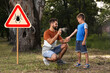 © New Africa - Man applying insect repellent on his son's leg in park near tick warning sign