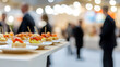 © A2Z AI  - A buffet table at a networking event showcases an array of beautifully arranged appetizers on white plates, set against a blurred background of attendees in business attire.