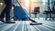 © Pete - Person vacuums carpet in office space with modern cleaning machine. Man cleans floor with equipment near chairs, maintaining hygiene. Professional janitorial service ensures clean workspace for
