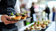 © A2Z AI  - A waiter gracefully presents a tray of gourmet canapés at an elegant event. The culinary artistry is evident in these delectable, miniature bites. A treat for your sight.