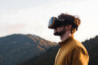 © A2Z AI  - Experiencing augmented reality in nature. A man uses a VR headset with mountain scenery in the background. Exploring digital worlds and the outdoors at the same time.