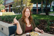 © Halfpoint - Plus size woman having lunch outdoors, eating noodles.