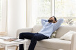 © fizkes - Serene African man relaxing with hands behind head on sofa