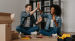 © Running opossum - young caucasian man and black woman celebrating success during home renovation with high five