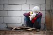 © ittipol - A construction worker sits against a wall, wearing a hard hat and safety gear