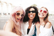 © halayalex - Three young beautiful smiling hipster female in trendy summer clothes.Sexy carefree multiracial women posing on the street background.Positive models having fun in sunglasses. Taking Pov selfie