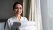© Salander Studio - a smiling hotel maid holding a stack of clean white towels