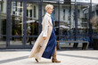 © Anna Zhukkova - Beautiful Woman Wearing Fashionable Spring Or Fall Clothes, beige trench coat, denim dress and high boots. Female stylish Model walking Street. Autumn trend street fashion style. Outdoors