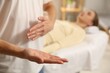 © New Africa - Reiki master showing his hand while healing patient's aura during therapy indoors, closeup