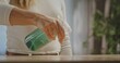 © kinomaster - A person cleaning a wooden surface using a spray bottle with green liquid. The scene suggests home cleaning or maintenance.