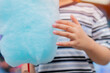 © Kunlathida - Cotton candy in the hand of a child in a summer park. Sweet food and sugar.