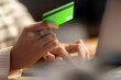 © Studio Marmellata - Crop anonymous young woman using green plastic card for online shopping on internet website at home