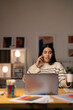 © Studio Marmellata - Young Arab female remote employee in casual clothes speaking via smartphone with client while working on project remotely using laptop