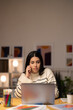 © Studio Marmellata - Young Arab female remote employee in casual clothes speaking via smartphone with client while working on project remotely using laptop