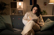 © Studio Marmellata - Concentrated Arab female in casual beige outfit and eyeglasses sitting on sofa with documents using laptop while working online at home