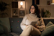© Studio Marmellata - Concentrated Arab female in casual beige outfit and eyeglasses sitting on sofa with documents using laptop while working online at home