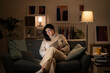 © Studio Marmellata - Concentrated Arab female in casual beige outfit and eyeglasses sitting on sofa with documents using laptop while working online at home