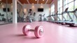 © Leonardo - Mancuerna rosa con brillo metálico colocada sobre un suelo de gimnasio de color rosa pastel suave