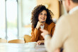 © bnenin - A Woman In Orange Blazer Smiles During Friendly Business Meeting In Cafe
