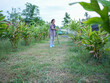 © buraratn - Young woman waters plants in lush garden, surrounded by vibrant greenery. She uses hose to nurture growing foliage, showcasing her dedication to gardening and nature