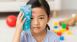 © SYATRI RAWU - A portrait of a sad Asian child with a painful bruise on her forehead applying a cold gel pack to the injury for first aid